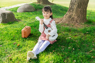 女孩在草坪上弹吉他图片