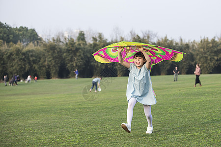 小女孩拿着风筝在草坪上奔跑图片