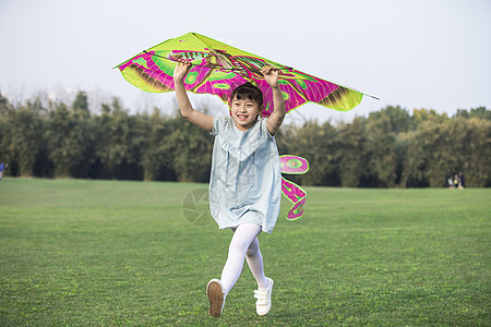 小女孩拿着风筝在草坪上奔跑图片