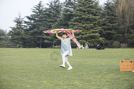 小女孩拿着风筝在草坪上奔跑图片