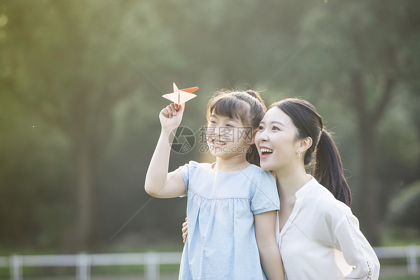 妈妈和女儿在草坪上玩纸飞机图片