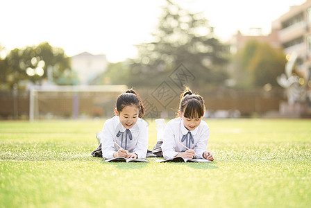 小学生趴在操场学习背景图片