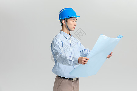 头戴安全帽看图纸的工程师背景图片
