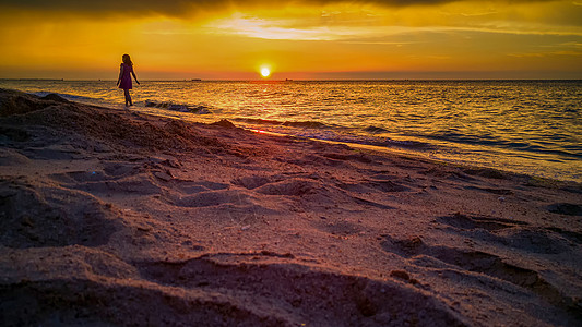 日落时分在沙滩上散步的人图片