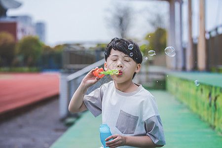 小男孩操场吹泡泡图片