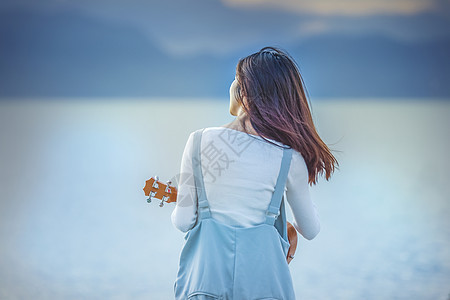 女孩休闲看海弹吉他背景图片