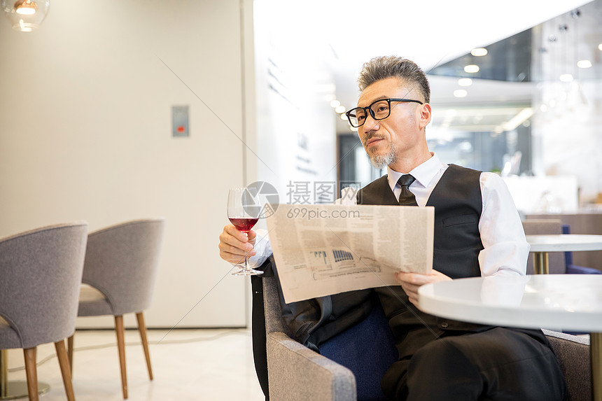 商务男士品红酒看报图片