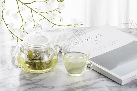 杂志和花绿茶与玻璃茶壶背景