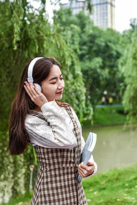 公园带耳机看书的女学生高清图片