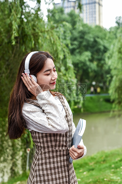 公园带耳机看书的女学生图片