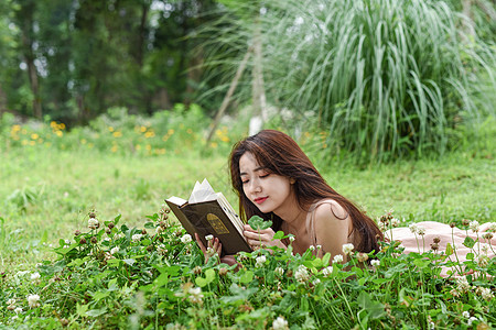 趴在花丛中看书的美女背景图片