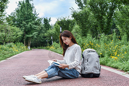 公园路边坐在地上看书学习的女同学背景