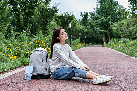 坐在路边看书休息的女学生背景图片