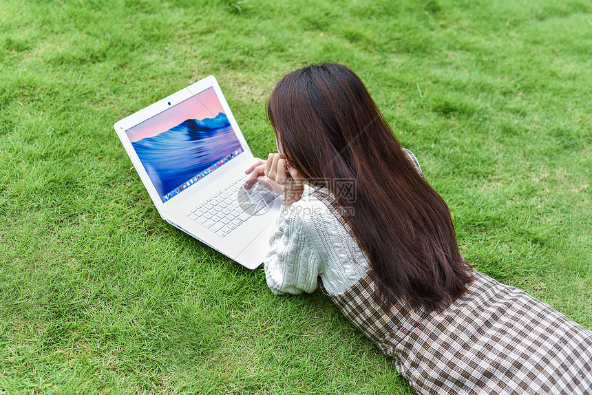 趴在草地玩电脑的女孩图片