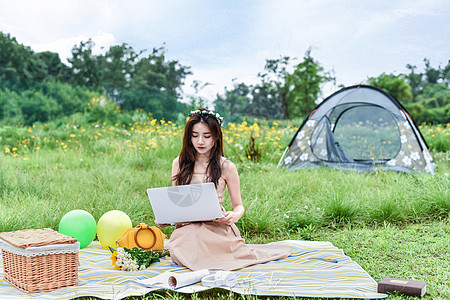坐在草坪上用电脑的女生背景图片