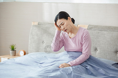 家庭主婦中年女性失眠头痛坐在床上背景
