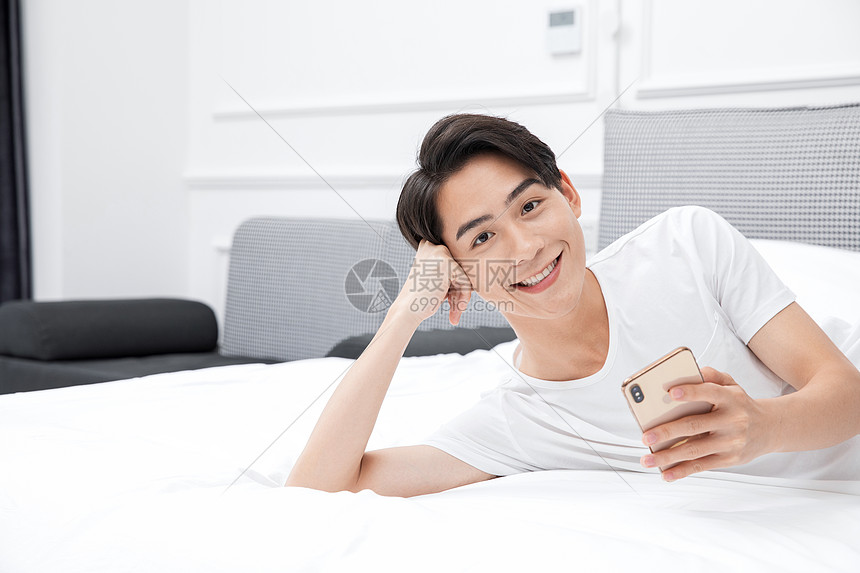 男青年卧室床上用手机图片