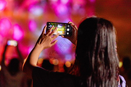 潮流美女用手机在音乐节拍照图片