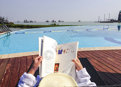 一个带草帽的女士躺在度假酒店泳池边休息的背影图片