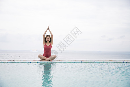 海边打坐海边泳池美女做瑜伽背景