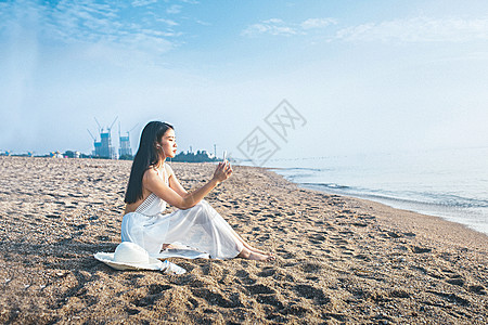 海边美女海边玩手机听音乐的美女背景