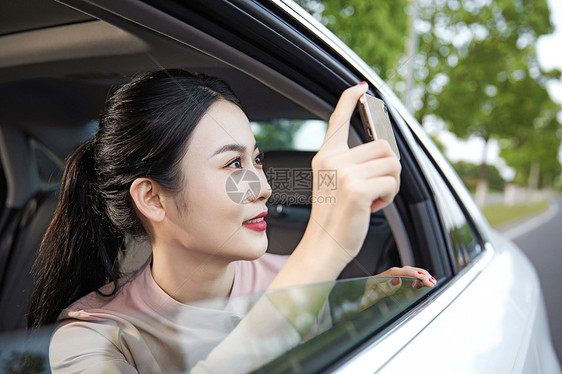 年轻女性在车内用手机拍照图片