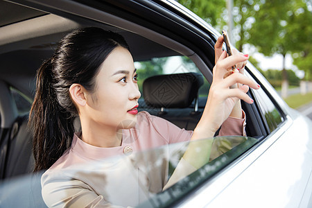 年轻女性在车内用手机拍照图片