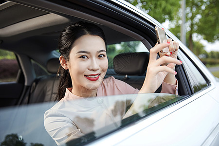 年轻女性在车内用手机拍照图片