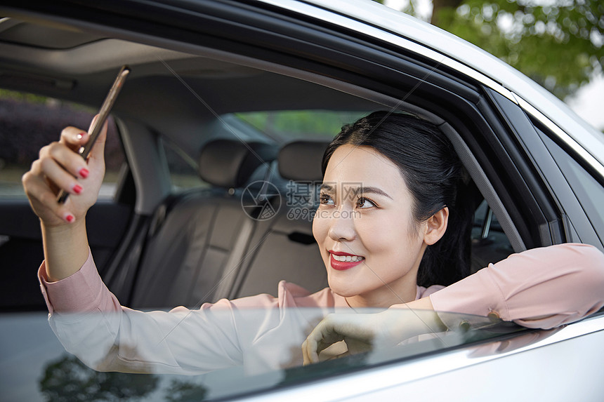 年轻女性在车内用手机拍照图片