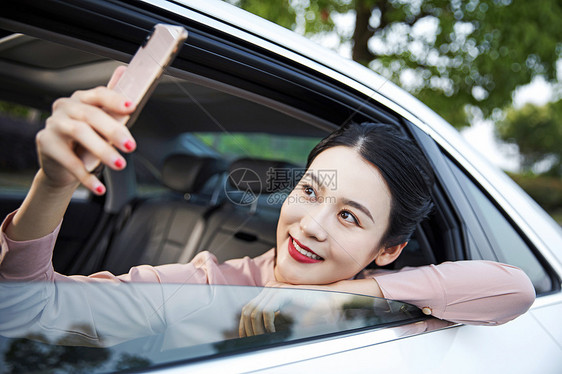 年轻女性在车内用手机拍照图片