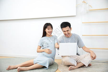 丈夫和孕妇开心的看着电脑图片