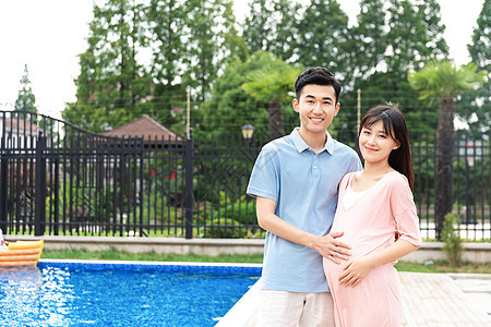 丈夫和孕妇在户外泳池旁散步图片