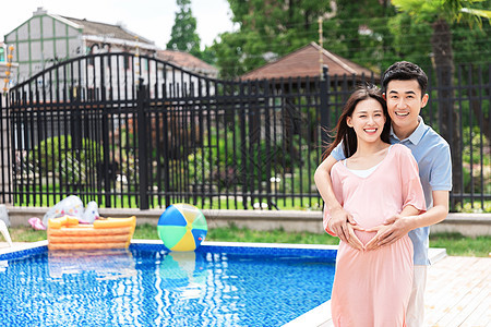 孕妇和丈夫在户外游泳池拥抱图片