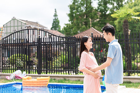 孕妇和丈夫面对面站在泳池旁图片