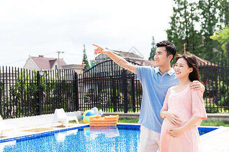 丈夫和孕妇一起站在户外泳池旁图片