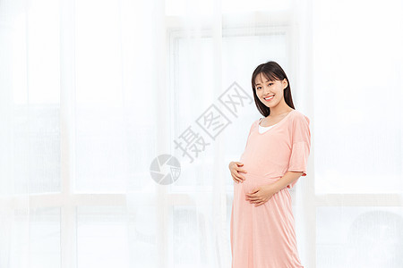 一个孕妇在客厅站着抚摸肚子图片