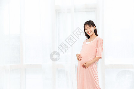 一个孕妇在客厅站着抚摸肚子背景图片