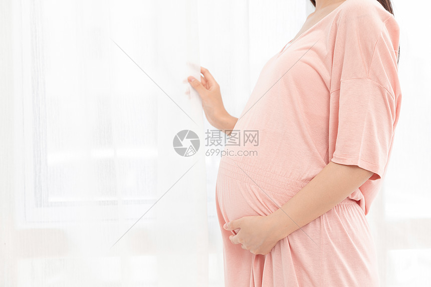一个孕妇在客厅站着抚摸肚子图片