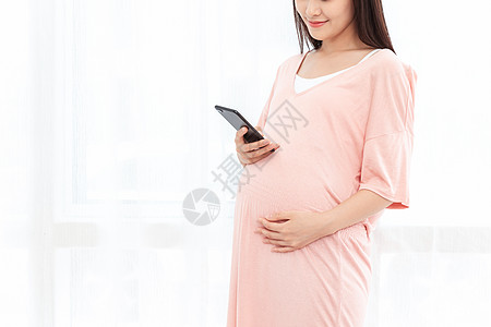 孕妇在客厅纱窗旁边使用手机背景图片