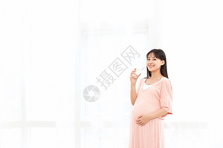 一个孕妇站着在客厅喝水图片