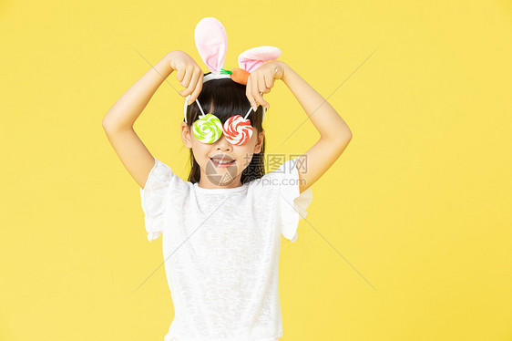 戴着兔耳朵的小女孩拿着糖果图片