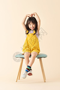 可爱小女孩坐在椅子上比心背景图片