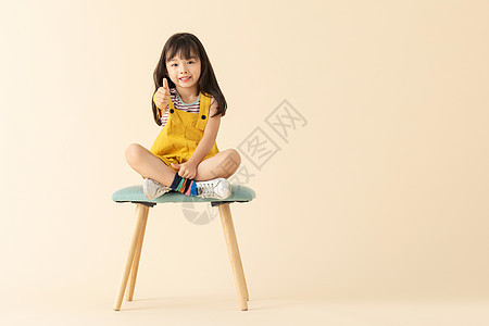 小女孩坐在椅子上微笑点赞图片
