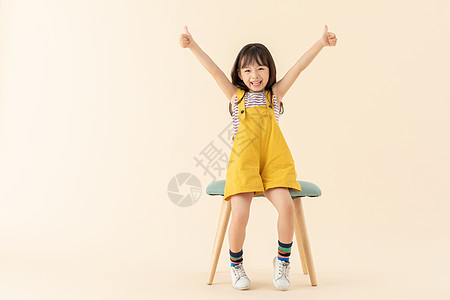 小女孩坐在椅子上微笑点赞背景图片