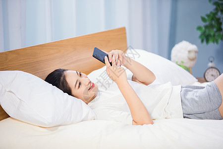 女性躺在床上玩手机图片