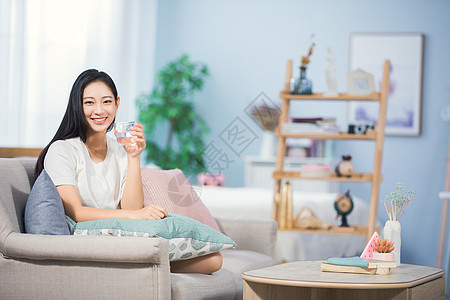 女性坐在沙发上喝水图片