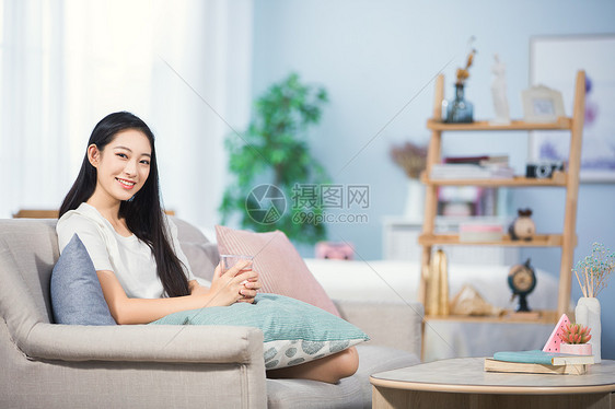 女性坐在沙发上喝水图片