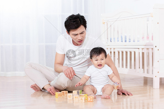 父亲陪伴婴儿在地板上玩耍图片