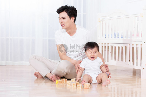 父亲陪伴婴儿在地板上玩耍图片
