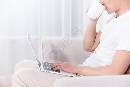男性坐在沙发上使用电脑特写图片